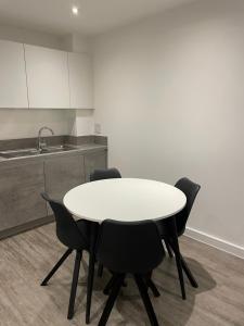 a white table and black chairs in a kitchen at Luxurious 2 Bedroom Apartment in Barking