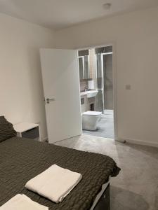 a bedroom with a bed and a bathroom with a toilet at Luxurious 2 Bedroom Apartment in Barking