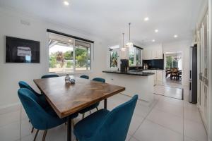a kitchen and dining room with a wooden table and blue chairs at High Vista in Mount Eliza with Pool in Mount Eliza