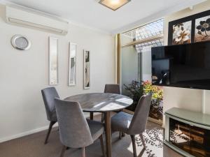 a dining room with a table and chairs and a tv at Yarrawonga Lakeside Apartment 25 in Mulwala