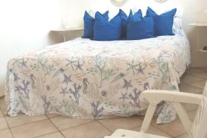 a bed with blue pillows and a white comforter at Ampio appartamento mare in Putzu Idu