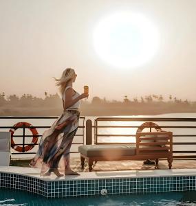 a woman is standing next to a swimming pool at NILE CRUISE NAJ Every Thursday from Luxor 4 nights & every Monday from Aswan 3 nights in Aswan