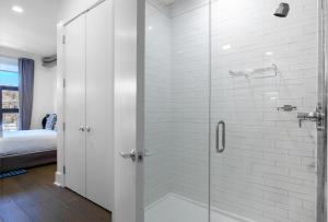 baño con ducha y puerta de cristal en Dharma Home Suites Hoboken, en Hoboken