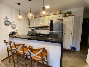 a kitchen with a counter with chairs and a refrigerator at Apartamento na Vila de Barra Grande - Bahia in Barra Grande