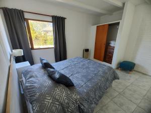 a bedroom with a bed with pillows and a window at Sol de montaña, Bariloche. in San Carlos de Bariloche