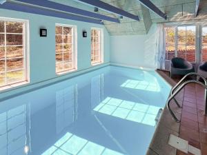 a swimming pool in a room with blue walls and windows at 12 person holiday home in Ringk bing in Søndervig