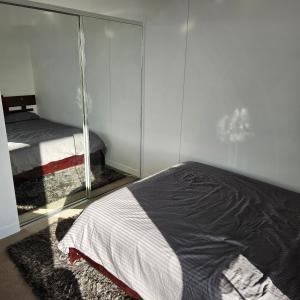 een slaapkamer met een bed en een spiegelwand bij Bedroom & Private Bathroom in Modern Inner Brisbane Apartment in Brisbane