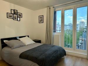 a bedroom with a bed and a large window at Magnifique logement pour 5P La Défense/l'Aréna in Nanterre
