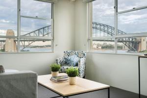 a living room with a chair and a table and windows at Harbourside #49 in Sydney