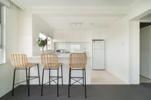 a kitchen with three bar stools and a counter with a refrigerator at Harbourside #49 in Sydney
