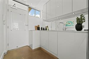 a white kitchen with a counter and a sink at Modern Potts Point Studio in Sydney