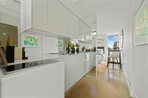 a kitchen with white counters and a dining room at Modern Potts Point Studio in Sydney