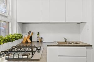 - une cuisine blanche avec cuisinière et évier dans l'établissement The Great Escape, Paddington apartment, à Sydney