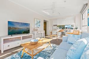 a living room with a blue couch and a tv at Harbourside #31 in Sydney