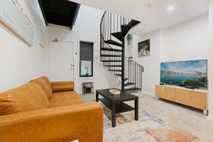 a living room with a couch and a spiral staircase at Cosy Camperdown in Sydney