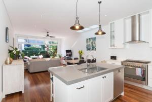 een keuken met een wastafel en een woonkamer bij Bright Home in Trendy Newtown close to the Park in Sydney