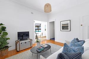 een woonkamer met een witte bank en een tafel bij Absolute Seafront Bronte in Sydney