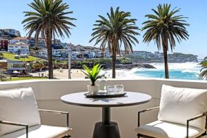 a table and chairs on a balcony with a view of the beach at Absolute Seafront Bronte in Sydney