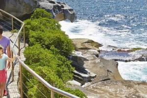 a woman and a child walking down a stairs near the ocean at Absolute Seafront Bronte in Sydney