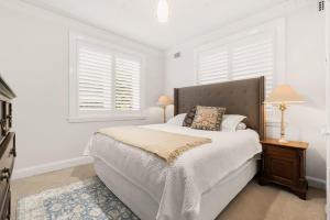 a white bedroom with a bed and two windows at Classic Art Deco in Sydney