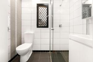 Baño blanco con aseo y lavamanos en Comfy Darlinghurst Retreat, en Sídney