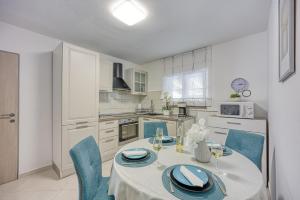 a white kitchen with a table and blue chairs at Villa Dana in Divšići