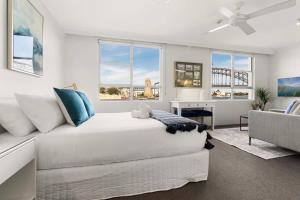 a white bedroom with a bed and a couch at Harbourside #15 in Sydney
