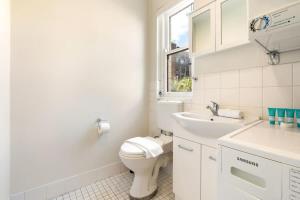 a white bathroom with a toilet and a sink at Top Floor Apartment with Harbour Views in Sydney