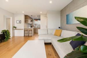 a living room with a white couch and a table at Coogee Beach Cosy Home in Sydney
