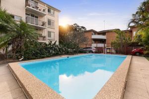 a large blue swimming pool in front of a building at Coogee Beach Cosy Home in Sydney