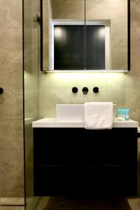 a bathroom with a white sink and a mirror at Lux & Quiet Apartment in, Potts Point in Sydney