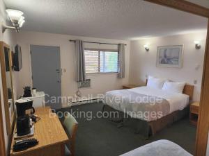 ein Hotelzimmer mit zwei Betten und einem Tisch in der Unterkunft Campbell River Lodge in Campbell River
