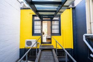 une maison jaune avec une porte et des escaliers jaunes dans l'établissement Darlinghurst Studio 1 VOGUE, à Sydney