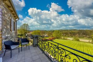 a balcony with two chairs and a view of a yard at Villa Stara Hiza in Novaki Pazinski