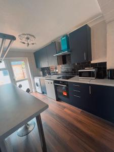 una cucina con armadi blu e pavimenti in legno di Hickory Haven a Borehamwood