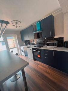 a kitchen with blue cabinets and a wooden floor at Hickory Haven in Borehamwood