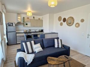 ein Wohnzimmer mit einem blauen Sofa und einer Küche in der Unterkunft L'Hacienda / F2 de standing Cergy /parking inclus in Cergy