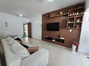 een woonkamer met een witte bank en een tv bij Apartamentos na Praia de Camboinha/ Cabedelo/João Pessoa in Cabedelo