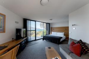 Cette chambre comprend un lit et une télévision. dans l'établissement Edge of the Bay Resort, à Coles Bay