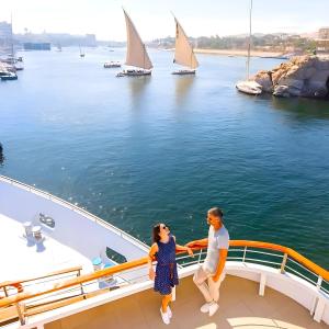 a couple standing on the deck of a yacht with sailboats at NILE CRUISE LUXOR & ASWAN نايل كروز الاقصر و اسوان in Luxor