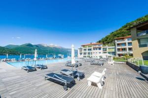 a resort with a pool and chairs and buildings at 4 bedroom apartment with pool & jacuzzi in Maccagno Inferiore