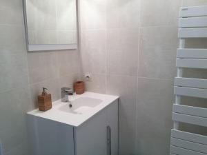 ein weißes Badezimmer mit einem Waschbecken und einem Spiegel in der Unterkunft DISNEYLAND Paris (5 min from the park) in Chessy
