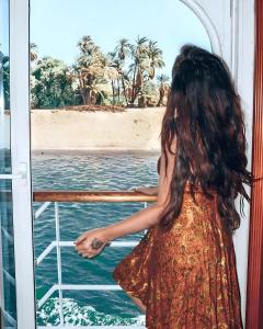 uma jovem olhando pela janela de um barco em Nile CRUISE NPS Every Monday from Luxor 4 nights & every Friday from Aswan 3 nights em Aswan