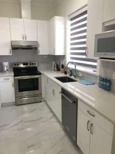 cocina con armarios blancos y fogones en Ground Lvl Brand New Suite - Two Bedroom, en Surrey