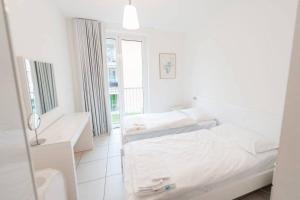 a white bedroom with two beds and a mirror at Modern 3 bedroom apartment on Lake Maggiore in Maccagno Inferiore
