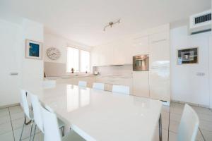 Maccagno InferioreにあるModern 3 bedroom apartment on Lake Maggioreの白いキッチン(長い白いテーブルと椅子付)