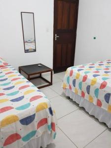 Cette chambre comprend 2 lits, une table et une porte. dans l'établissement 1Mar doce lar Japaratinga-AL, à Japaratinga