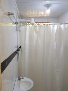 La salle de bains est pourvue d'un lavabo et d'un rideau de douche. dans l'établissement 1Mar doce lar Japaratinga-AL, à Japaratinga