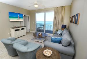 sala de estar con sofá, sillas y TV en Beachfront Oasis at Splash Resort and Condos en Panama City Beach