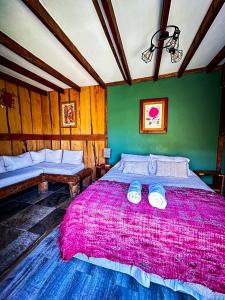 a bedroom with a large bed with a pink blanket at Cabañas Pewma Futrono in Futrono